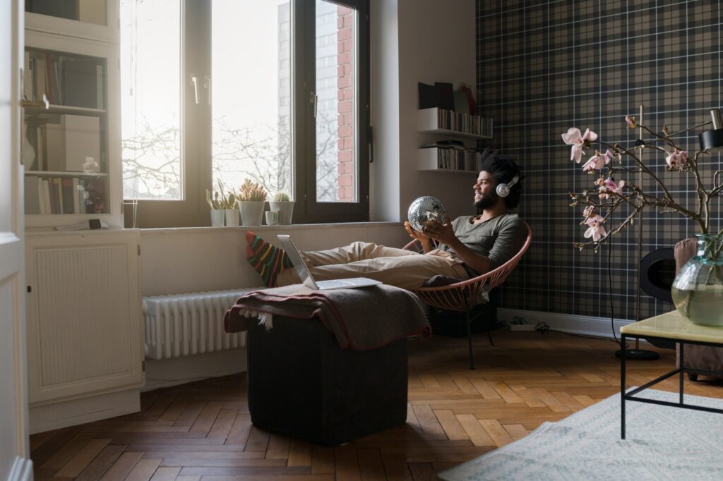 Man sitting in living room in armchair holding mirror ball listening to music